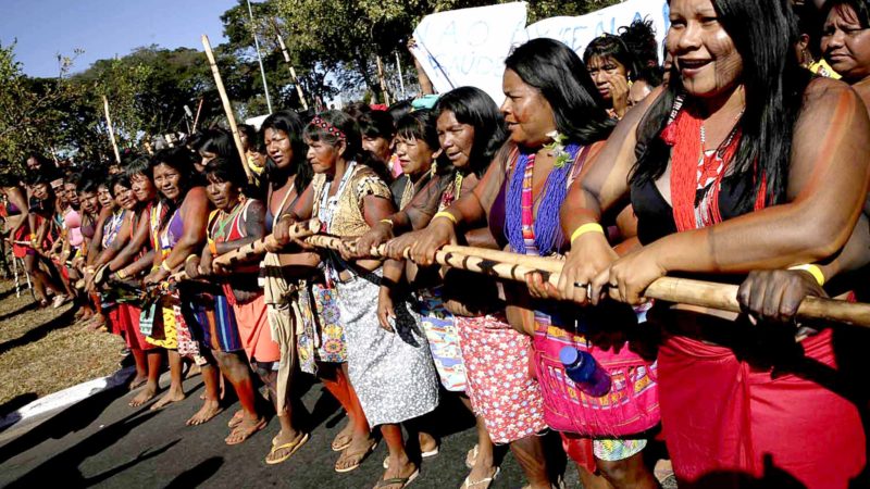 Indigenous women stand together in the Indigenous Women's Health March, in Brasilia, Brazil, Monday, Aug. 12, 2019. Indigenous women in traditional attire and painted faces are taking part in a multiday encampment in Brasilia aimed at highlighting indigenous rights issues.(AP Photo/Eraldo Peres)