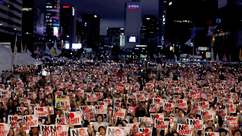 In this Aug. 15, 2019 photo, protesters hold candles and signs during a rally denouncing Japanese Prime Minister Shinzo Abe and also demanding the South Korean government to abolish the General Security of Military Information Agreement, or GSOMIA, an intelligence-sharing agreement between South Korea and Japan, in downtown Seoul, South Korea. South Korea and Japan have locked themselves in a highly-public dispute over history and trade that in a span of weeks saw their relations sink to a low unseen in decades.  The letters read "No Abe." (AP Photo/Lee Jin-man)