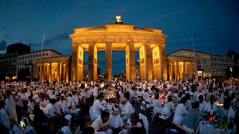 TOPSHOT - People dressed in white clothes take part in the "Diner en Blanc" social dining event in front of Berlin's landmark the Brandenburg Gate on August 10, 2019. - The "Diner en Blanc" concept, initiated by Frenchmen Francois Pasquier and carried out for the first time in 1988, is an event in which people dressed in white meet in a public space, generally an iconic location, to dine together. (Photo by Paul Zinken / dpa / AFP) / Germany OUT