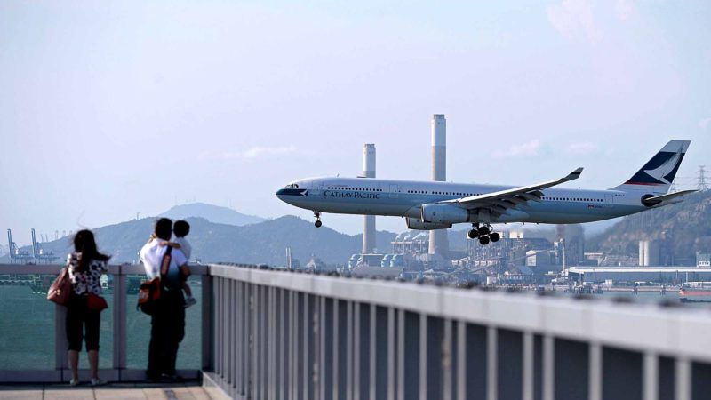 (FILES) This file photo taken on August 10, 2014 shows people watching a Cathay Pacific passenger plane land at Hong Kong's international airport. - Shares in Hong Kong's flagship carrier Cathay Pacific plunged more than four percent on August 12, 2019, after Beijing banned airline staff supporting Hong Kong protesters from flights going through the mainland. (Photo by Dale DE LA REY / AFP)