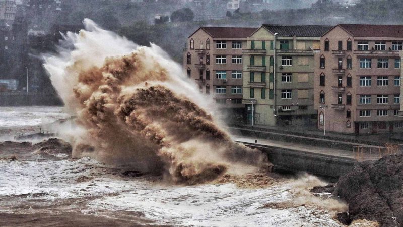 (FILES) This file photo taken on August 9, 2019 shows waves hitting a sea wall in front of buildings in Taizhou, China's eastern Zhejiang province. - The death toll rose to 43 as Typhoon Lekima slammed the eastern China coast, state media said on August 12, 2019, after the storm triggered a landslide, destroyed homes and forced the evacuation of more than a million residents. (Photo by STR / AFP) / China OUT