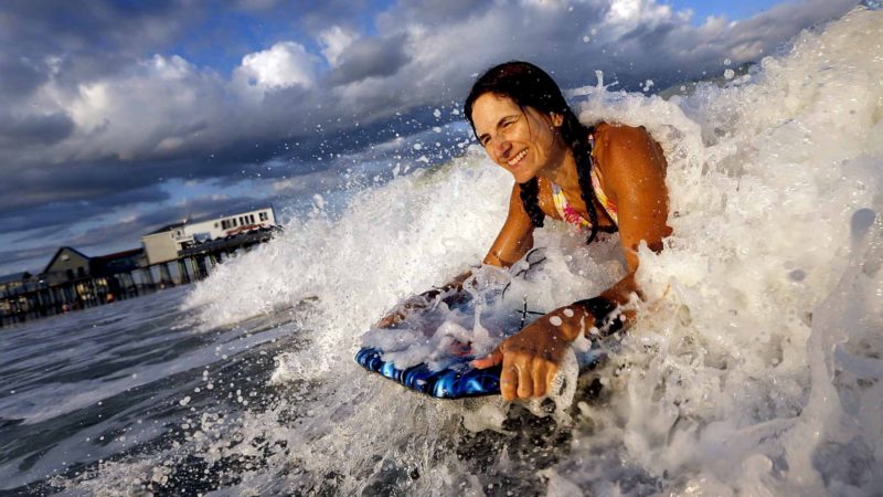 April Nice, of Cars, New Brunswick, Canada, rides a wave, Thursday, Aug. 29, 2019, near The Pier at Old Orchard Beach, Maine. The usually cold Atlantic Ocean has warmed up to a tolerable level just in time for Labor Day weekend. (AP Photo/Robert F. Bukaty)