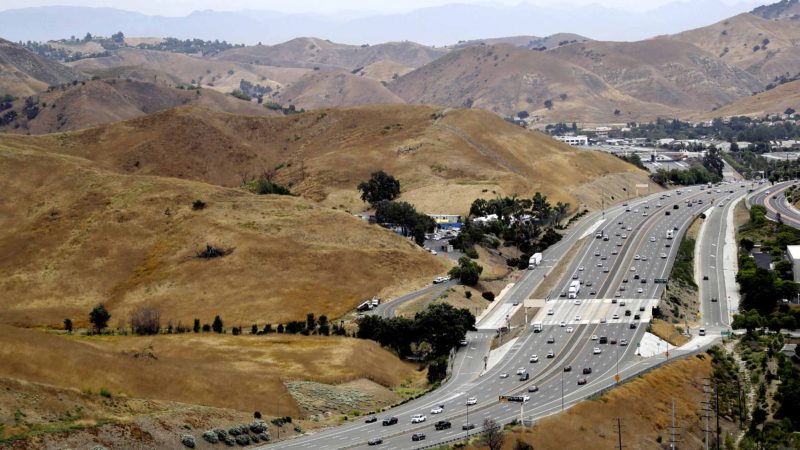 In this July 25, 2019, photo, U.S. Highway 101 passes between two separate open space preserves on conservancy lands in the Santa Monica Mountains in Agoura Hills, Calif. Hoping to fend off the extinction of mountain lions and other species that require room to roam, transportation officials and conservationists will build a mostly privately funded wildlife crossing over this freeway. It will give big cats, coyotes, deer, lizards, snakes and other creatures a safe route to open space and better access to food and potential mates. (AP Photo/Marcio Jose Sanchez)