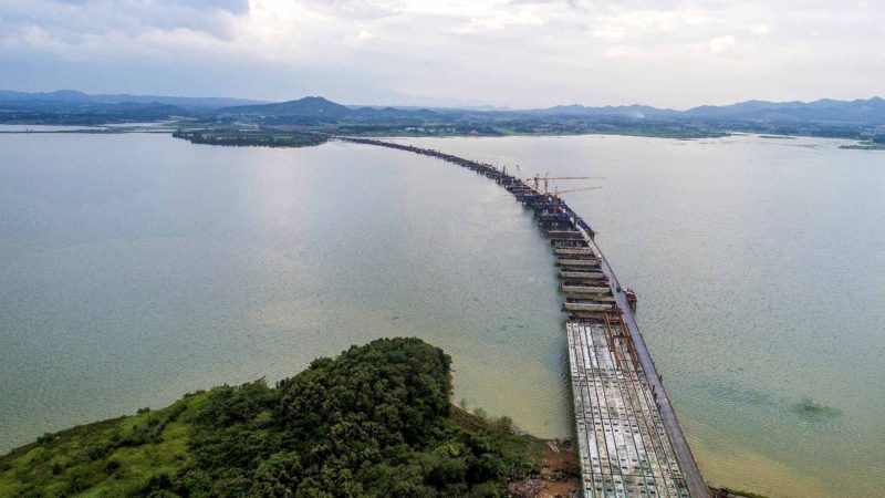 (190811) -- JIUJIANG, Aug. 11, 2019 (Xinhua) -- Aerial photo taken on Aug. 10, 2019 shows the construction site of the Xinmiao Lake Grand Bridge in Duchang County of Jiujiang, east China's Jiangxi Province. The Xinmiao Lake Grand Bridge under construction is designed to be 2,292.5 meters long with six lanes. After completion, the bridge will play an important role in improving regional transport and promoting tourism. (Xinhua/Yang Wenbin)