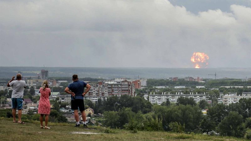 In this photo taken on Monday, Aug. 5, 2019, people watch and photograph explosions at a military ammunition depot near the city of Achinsk in eastern Siberia's Krasnoyarsk region, in Achinsk, Russia. Russian officials say powerful explosions at a military depot in Siberia left 12 people injured and one missing and forced over 16,500 people to leave their homes. (AP Photo/Dmitry Dub)