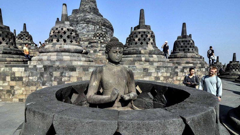 In this Monday, Aug. 12, 2019, photo, tourists inspect a Buddha statue at Borobudur Temple in Magelang, Central Java, Indonesia. The Indonesian city of Yogyakarta and its hinterland are packed with tourist attractions, including Buddhist and Hindu temples of World Heritage. Yet many tourists still bypass the congested city and head to the relaxing beaches of Bali. Recently re-elected President Joko Widodo wants to change this dynamic by pushing ahead with creating "10 new Balis," an ambitious plan to boost tourism and diversify South Asia's largest economy. (AP Photo/Slamet Riyadi)