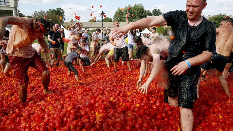 People throw tomatoes at each other as they take part in the first in Russian Tomatina battle in St.Petersburg, Russia, Sunday, Aug. 18, 2019. (AP Photo/Dmitri Lovetsky)