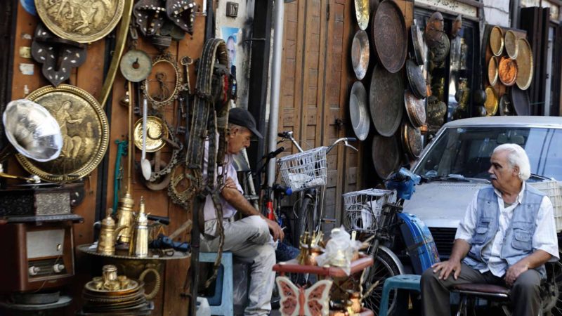 An crafstman chats with a visitor in front of his shop at the Bzourieh market in the centre of the Syrian capital Damascus. The declining value of the pound is a sure sign of Syria's ailing economy.  The civil war has battered the country's finances and depleted its foreign reserves.  A flurry of international sanctions on President Bashar al-Assad's regime and associated businessmen since the start of the war in 2011 has compounded the situation. Photo /RSS