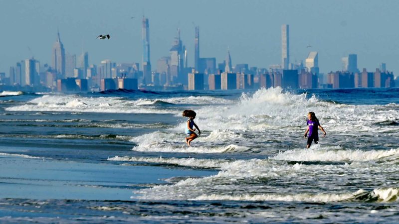 Children jump in the waves at the beach in front of the skyline of Lower Manhattan on September 17, 2019 in Long Branch, New Jersey. AFP/RSS.
