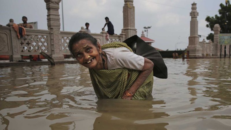 An elderly woman wades through waters of the swollen River Ganges in Varanasi, India. Heavy monsoon rains have raised the water level of the Ganges River above the danger level, triggering evacuation of thousands of people from flooded homes around the area. AP Photo/RSS