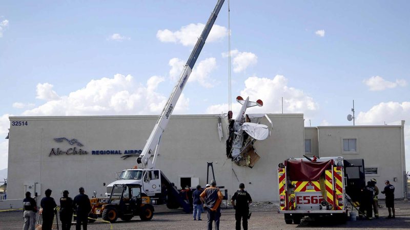 Police and fire personnel look on as workers remove a single-engine plane after it crashed into the terminal building shortly after takeoff at the Ak-Chin Regional Airport Tuesday, Sept. 10, 2019, in Maricopa, Ariz. The two people onboard suffered non-life-threatening injuries. (AP Photo/Ross D. Franklin)