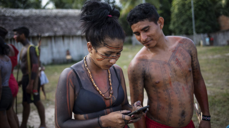 A woman checks her cell phone during a meeting of Tembé tribes at the Tekohaw indigenous reserve, Para state, Brazil. Some saw hope in the sustainable development plan presented this week at the meeting in the village of Tekohaw. It would include drones and other technology to curb the encroachers. AP Photo/RSS