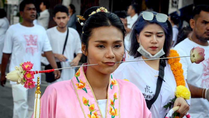 A devotee of a Chinese shrine with a sharp object pierced through her cheeks takes part in a procession during the annual Vegetarian Festival in Phuket on October 3, 2019. - The festival begins on the first evening of the ninth lunar month and lasts for nine days, with many religious devotees slashing themselves with swords, piercing their cheeks with sharp objects and committing other painful acts to purify themselves, taking on the sins of the community. (Photo by Mladen ANTONOV / AFP)