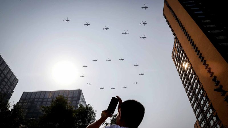 A man uses his smartphone to film Chinese army attack helicopters form a number "70" flying past capital city during a parade to commemorate the 70th anniversary of the founding of Communist China in Beijing, Tuesday, Oct. 1, 2019. China's Communist Party is celebrating its 70th anniversary in power with a parade showcasing its economic development and newest weapons. The event marks the anniversary of the Oct. 1, 1949, announcement of the founding of the People's Republic of China by then-leader Mao Zedong. (AP Photo/Andy Wong)