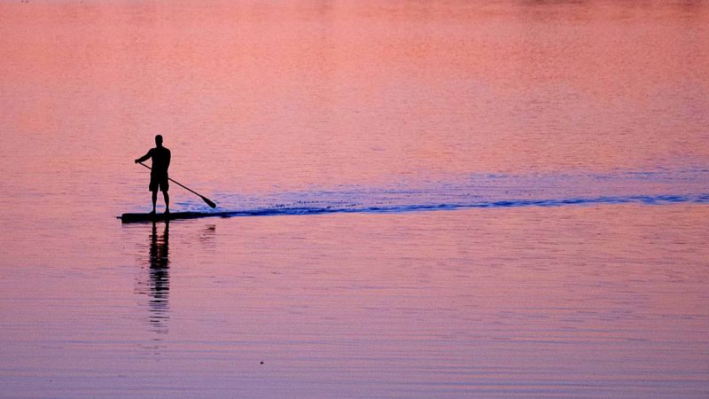 A man paddles a stand up paddle board toward shore during sunset on the Ottawa river Tuesday, Oct. 8, 2019 in Ottawa, Ontario. (Adrian Wyld/The Canadian Press via AP)