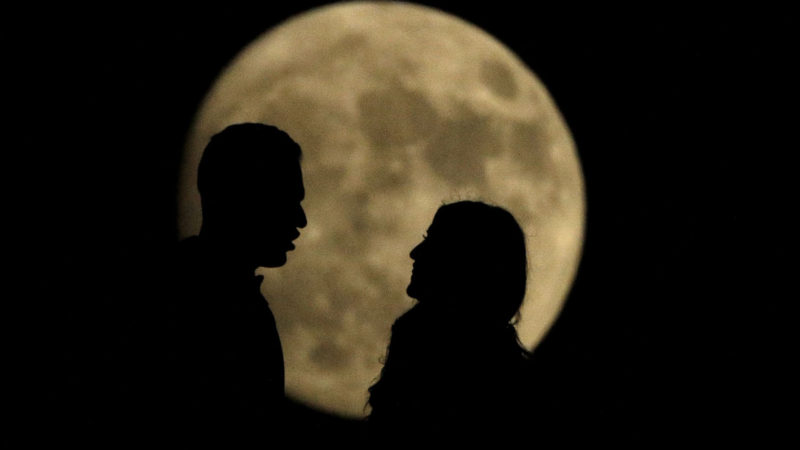 A couple talk while watching the nearly full moon rise from a vantage point at the National WWI Museum and Memorial, Sunday, Nov. 10, 2019, in Kansas City, Mo. (AP Photo/Charlie Riedel)