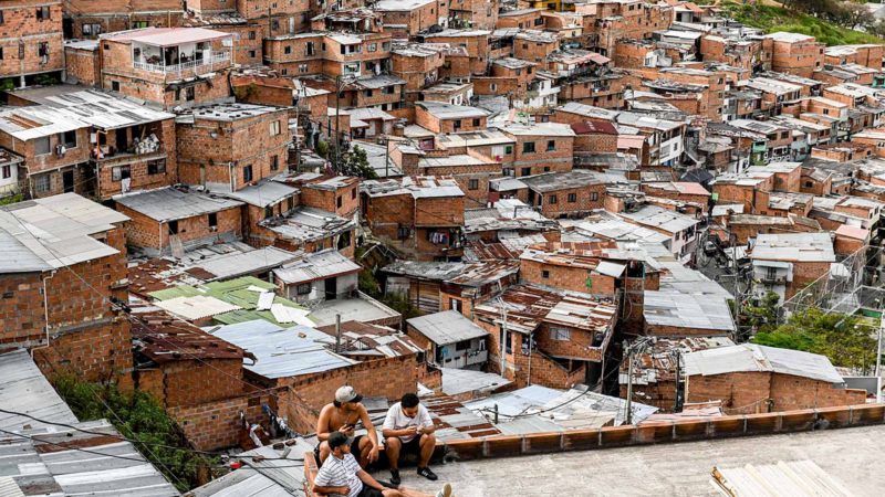 Residents rest at a terrace of the Comuna 13 neighborhood in Medellin, Colombia, on November 15, 2019. - With 25,000 monthly visits, tourism has become an arm to dissuade violence in Medellin. (Photo by JOAQUIN SARMIENTO / AFP)