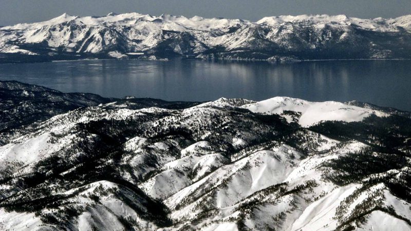 In this March 2, 2017 aerial photo, record winter snowfall is seen in the mountains around Lake Tahoe, viewed from above the Washoe Valley just south of Reno, Nev. Winter recreationists at Lake Tahoe are lining up on opposite sides of Forest Service plans that would close some areas to snowmobiles while opening others currently off limits to motorized use. The Forest Service has extended its public comment period on the snow travel management plan through Dec. 9, 2019. (AP Photo/Scott Sonner, File)