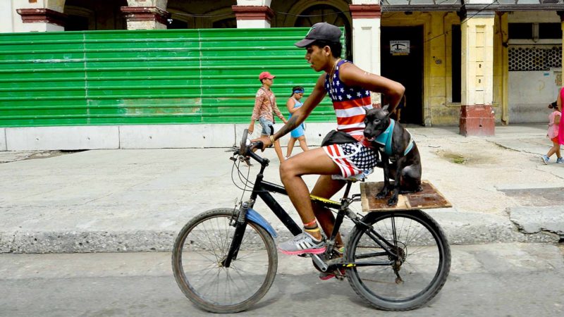 A man wearing a shirt depicting the US flag rides in his bicycle along a street of Havana, on December 12, 2019. - Cuba and the United States, former enemies of the Cold War, had a historic approach five years ago, but their relations deteriorated after the election of Donald Trump, who reinforced sanctions against the island. (Photo by YAMIL LAGE / AFP)
