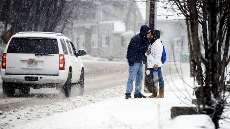 A couple leans in for a quick kiss while walking in the snow on Westminster Street in Fitchburg, Mass., during the storm in the area Monday, Dec. 30, 2019. (Ashley Green/Worcester Telegram & Gazette via AP)
