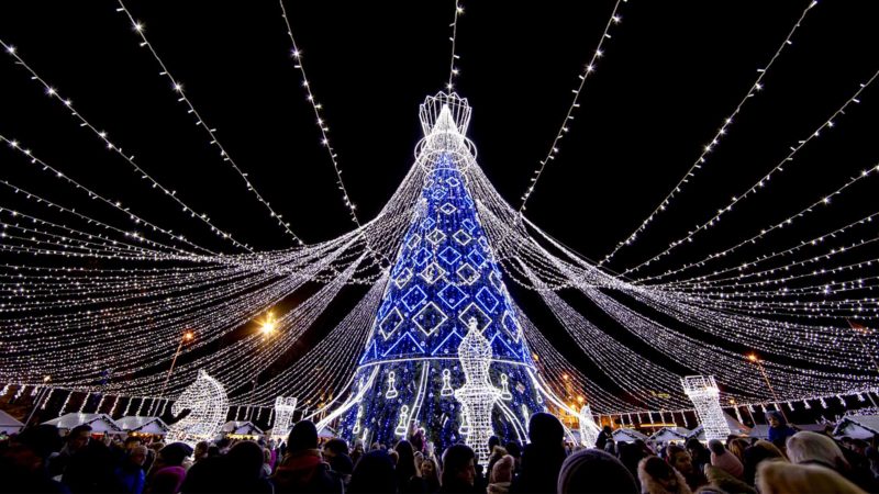 People walk by an illuminated Christmas tree at Cathedral Square in Vilnius, Lithuania, Sunday, Dec. 1, 2019. (AP Photo/Mindaugas Kulbis)