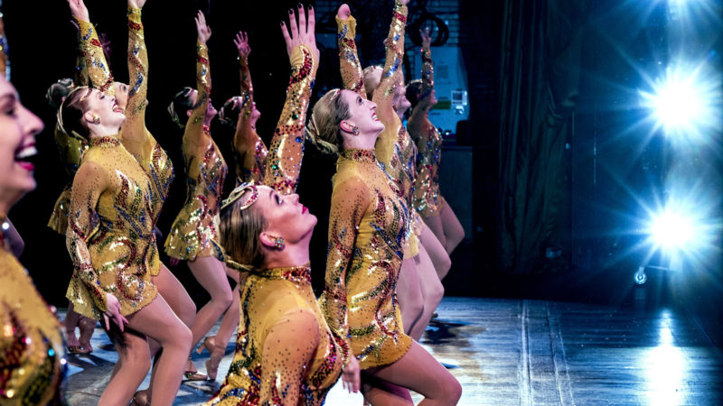 In this Monday, Nov. 25, 2019 photo, Rockette Sydney Mesher, front center, dances during a performance of the Christmas Spectacular at Radio City Music Hall in New York.  Mesher, who was born without a left hand due to the rare congenital condition symbrachydactyly, is the first person with a visible disability ever hired by New York's famed Radio City Rockettes. (AP Photo/Craig Ruttle)