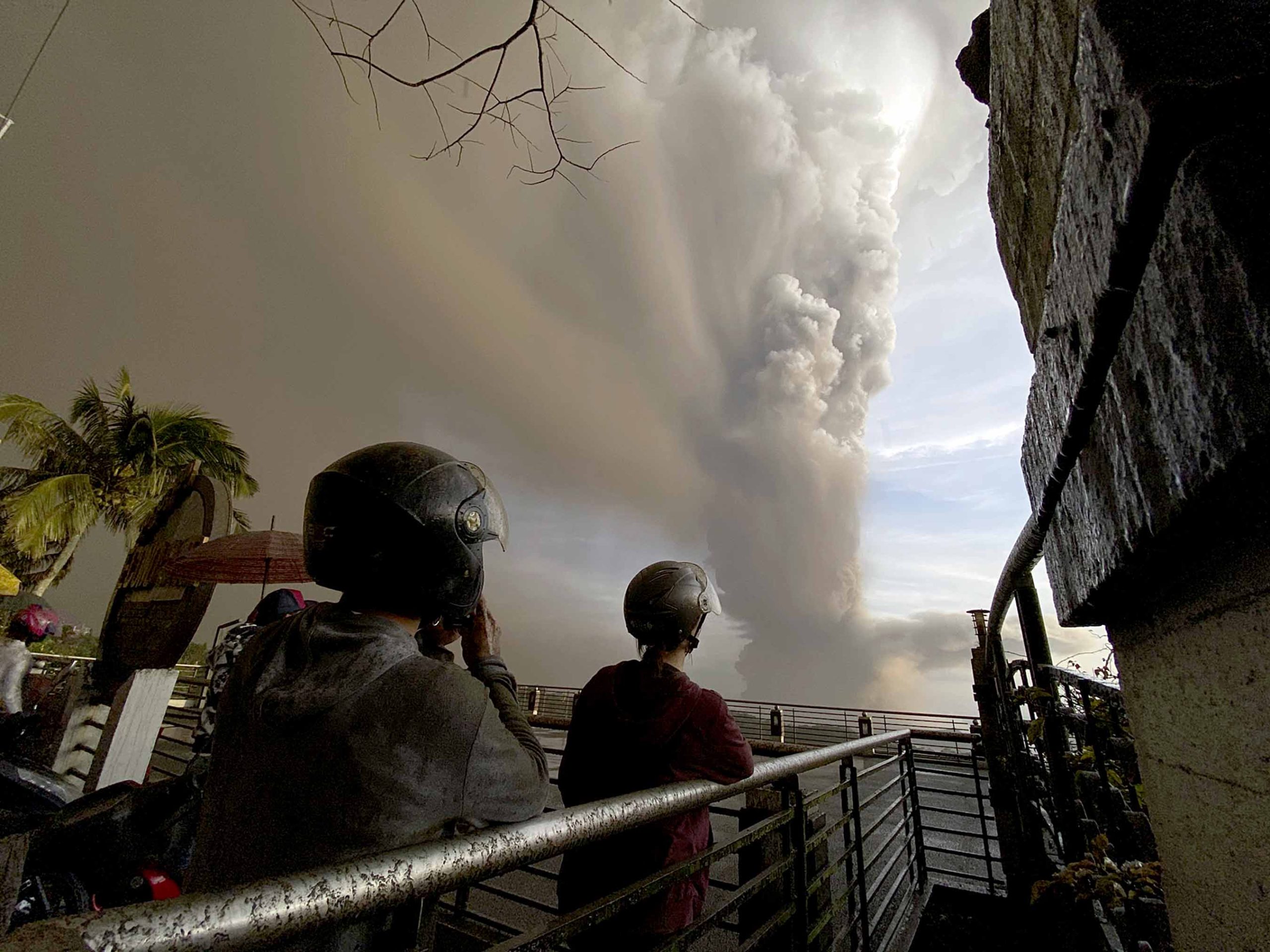 In this Jan. 12, 2020, photo, people watch plumes of smoke and ash rise from as Taal volcano erupts in Tagaytay, Cavite province, outside Manila, Philippines. (AP Photo/Aaron Favila, File)
