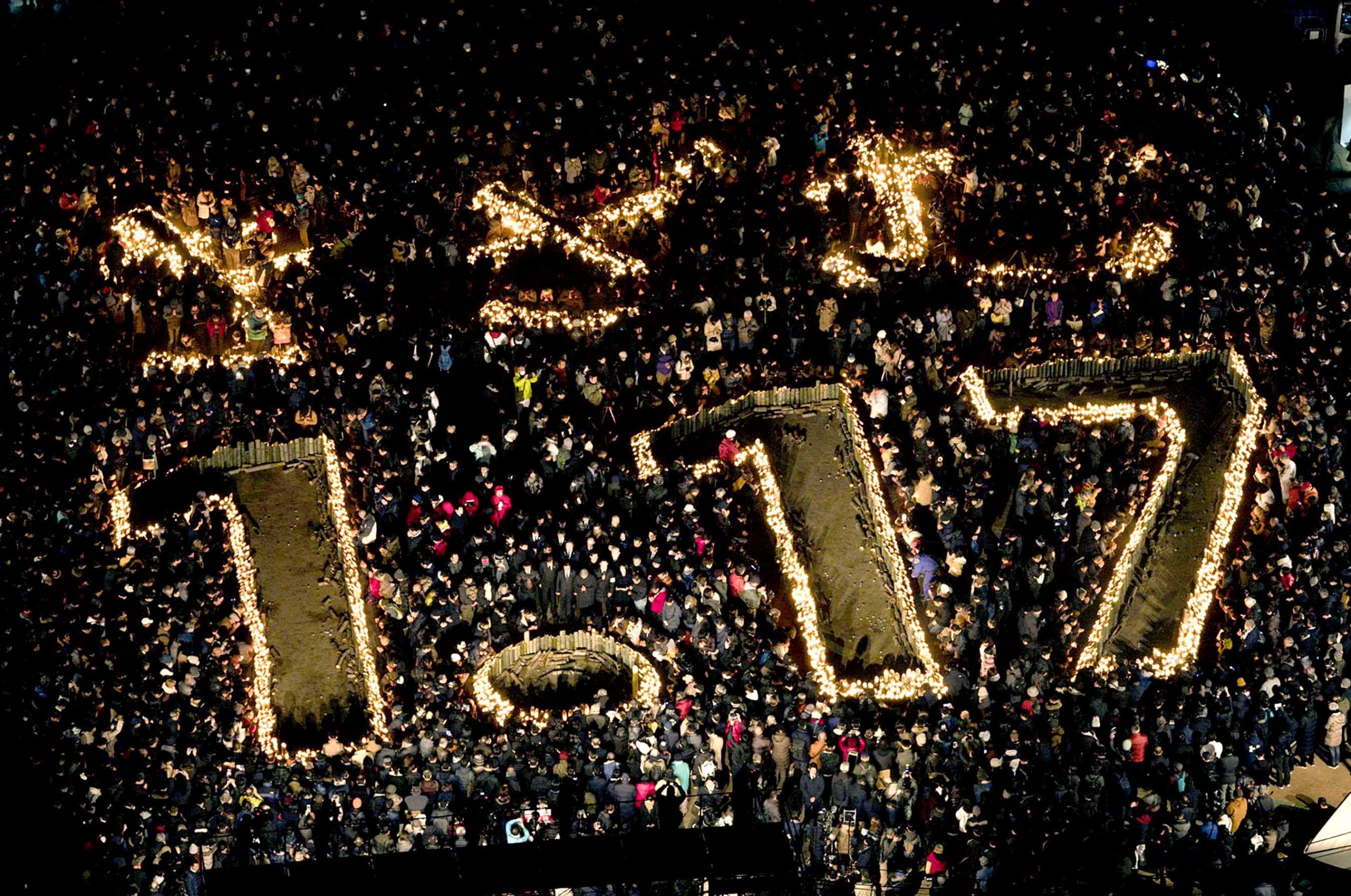 Candles are lit to form the date when a powerful earthquake that struck this western port city of Kobe on Jan. 17, 1995, at a park in Kobe, Japan, on Friday, Jan. 17, 2020 as people pray for the victims of the quake. Japan marks the 25th anniversary of Kobe earthquake which killed more than six thousand people and destroyed much of their city.(Nobuki Ito/Kyodo News via AP)