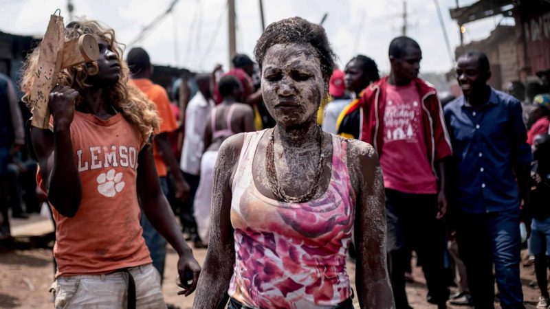 Nancy Nasaka, sister of 18-year-old Isaac Namolo (not in picture), from Gisu tribe, is smeared by local brew as she waits for her brother's circumsicion at Kibera slum in Nairobi, Kenya, on January 6, 2020. (Photo by Gordwin ODHIAMBO / AFP)