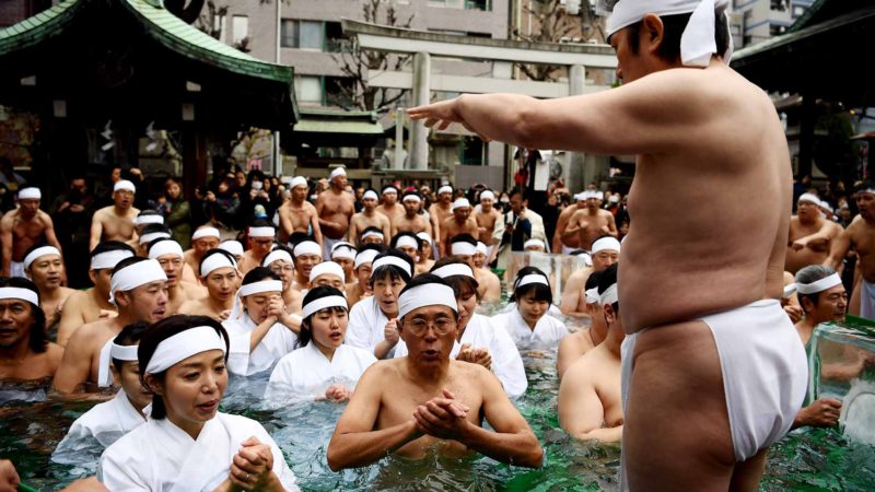 Shinto believers of the Teppozu Inari Shrine take a bath in cold water to purify their souls and bodies while others gesture around the pool during a New Year ritual in Tokyo on January 12, 2020. - Some 100 Shinto believers took part in the annual ritual. (Photo by CHARLY TRIBALLEAU / AFP)