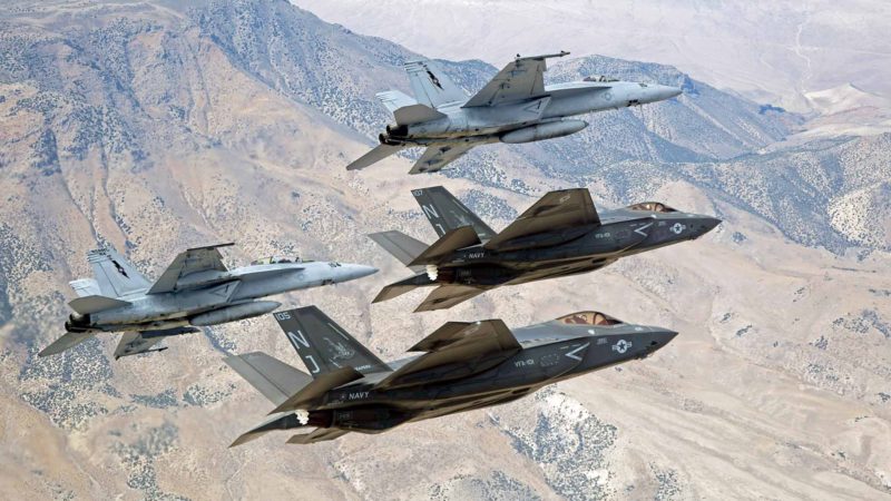 FILE - In this Sept. 3, 2015, file photo provided by the U.S. Navy, F-35C Lightning IIs, attached to the Grim Reapers of Strike Fighter Squadron (VFA) 101, and F/A-18E/F Super Hornets attached to the Naval Aviation Warfighter Development Center (NAWDC) fly over Naval Air Station Fallon's (NASF) Range Training Complex near Fallon, Nev. The U.S. Navy has concluded no significant environmental harm would result from its proposed tripling of the size of a Nevada bombing training range opposed by neighboring tribes, conservationists and at least one Democratic presidential candidate. (Lt. Cmdr. Darin Russell/U.S. Navy via AP, File)