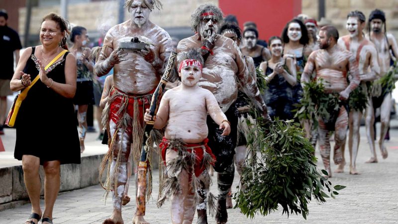 Aboriginal people carry a small fire at the beginning of the Wugulora Indigenous Morning Ceremony as part of Australia Day celebrations in Sydney, Australia, Sunday, Jan. 26, 2020. (AP Photo/Rick Rycroft)