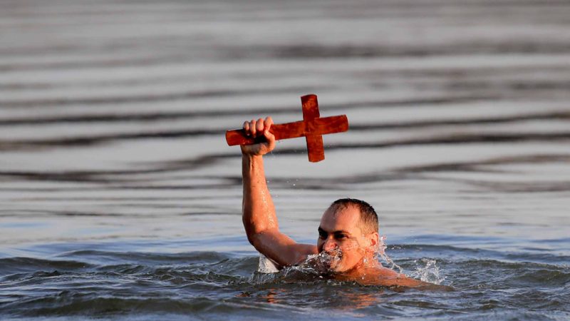 A man holds one of three wooden crosses, thrown by Orthodox archbishop Teodosie in the Danube river for men to swim and retrieve them, during a religious service in Harsova, Romania, Sunday, Jan. 5, 2020, a day ahead the celebration of Epiphany. More than 200 thousand bottles were filled with holy water in the Black Sea port of Constanta as Orthodox Romanians prepare to celebrate epiphany on Jan. 6. (AP Photo/Vadim Ghirda)