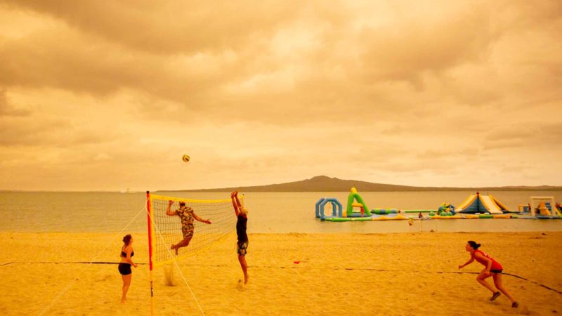 (200107) -- BEIJING, Jan. 7, 2020 (Xinhua) -- People play beach volleyball at the Mission Bay under an orange-colored sky as smoke generated by Australian bushfires hit Auckland, New Zealand, Jan. 5, 2020.
 The heavy smoke from devastating Australian bushfires cloaked Auckland, turning the city's skyline into eerie orange color on Sunday afternoon. (Photo by Li Qiaoqiao/Xinhua)