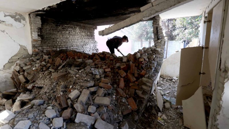 Vjollca Mesiti, 49, rummages through the ruins of her bakery to salvage bread baking pans in Thumane, northwest of the capital Tirana, on January 31, 2020. - A 6,4 magnitude quake shook Albania on November 26, 2019, the most deadly and destructive in four decades, leaving 51 lives lost and more than 15,000 people displaced. Nearly 90 buildings were reduced to rubble while more than 80,000 were damaged. The most damaged area was Albania’s second city of Durres, on the Adriatic coast, and the nearby town of Thumane, where scores of people were trapped beneath the ruins of apartment buildings and hotels. As the country struggles to put the pieces back together, it is facing a structural reality that the disaster exposed: the scourge of illegal construction that has allowed unsafe homes to sprout up across the poor Balkan country. (Photo by Gent SHKULLAKU / AFP)