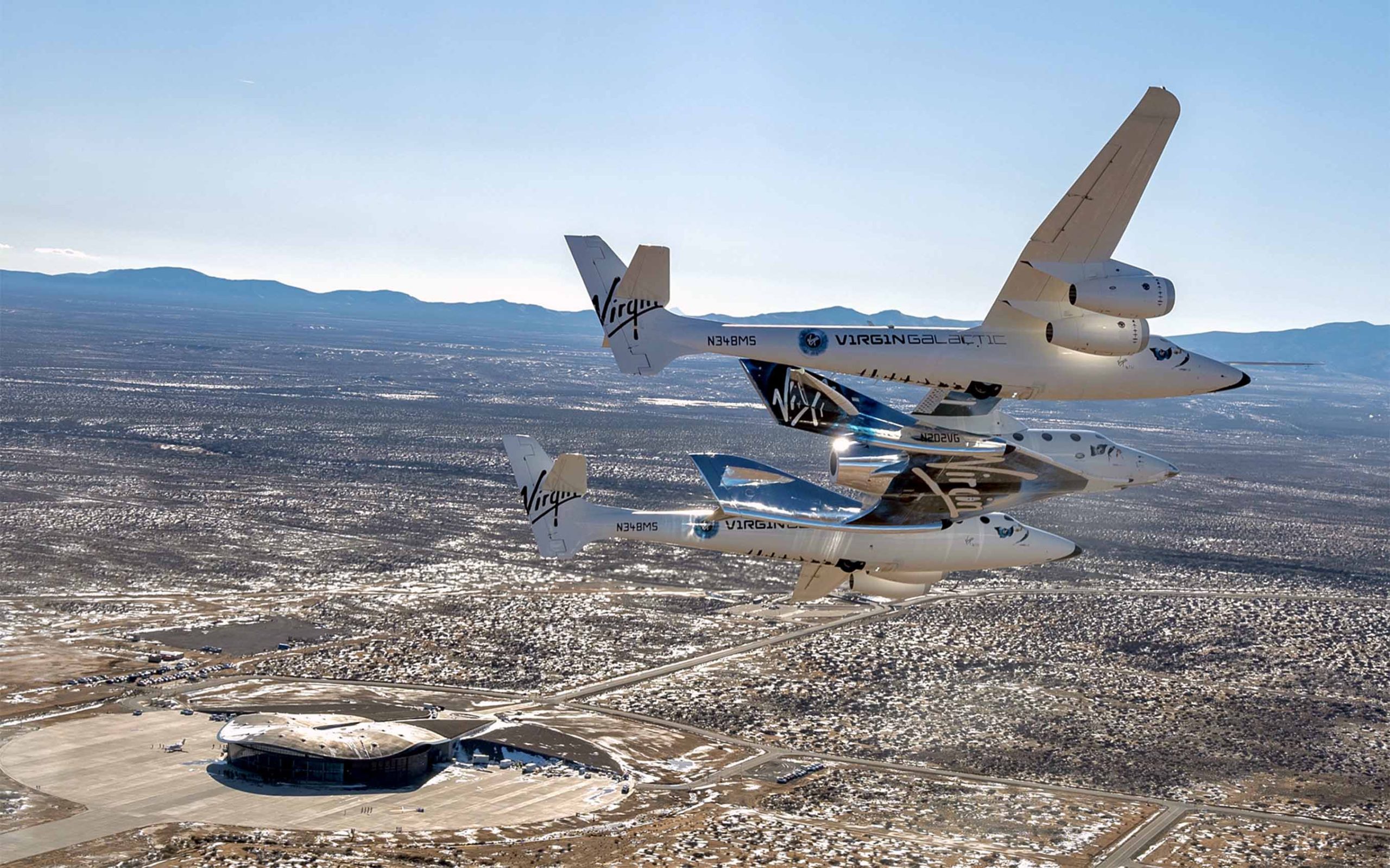 This photo provided by Virgin Galactic shows the Virgin Galactic's VSS Unity flying over Spaceport America in Truth or Consequences, NM on Thursday, Feb. 13, 2020. Virgin Galactic's spaceship VSS Unity, tucked under the wing of its special carrier aircraft, headed east from Southern California on a long-awaited ferry flight to its new home in New Mexico where it will be prepared for commercial operations carrying tourists on hops into space, the company said. (Virgin Galactic via AP)