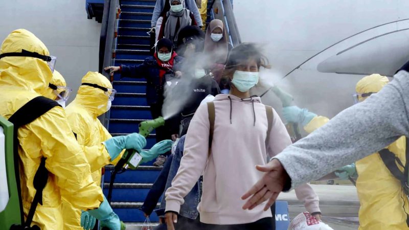 FILE - In this Sunday, Feb. 2, 2020, file photo released by the Indonesian Foreign Ministry, Indonesians who arrived from Wuhan, China, are sprayed with antiseptic at Hang Nadim Airport in Batam, Indonesia. Health authorities are scrambling to halt the spread of a new virus that has killed hundreds in China. But with important details about the illness and how it spreads still unknown, officials and medical personnel are struggling. (Indonesian Foreign Ministry via AP)