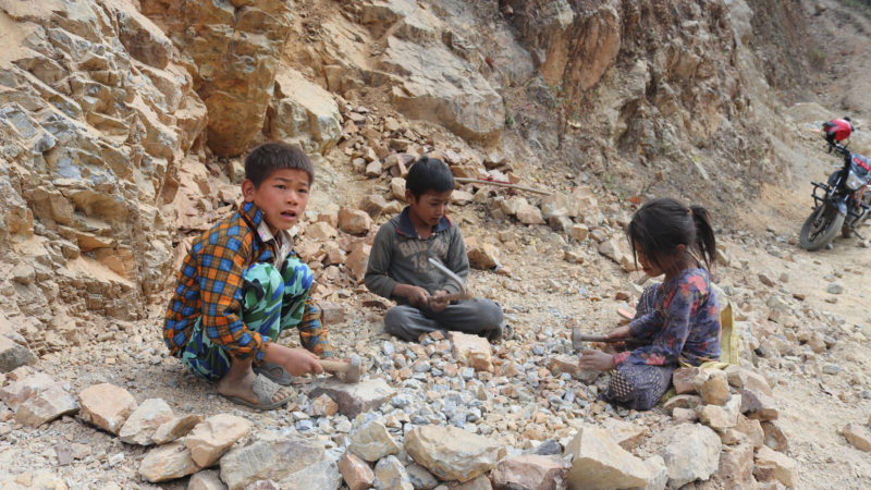 भेरी नगरपालिका–२ बाहुनथानास्थित शंकर भवन माविमा कक्षा २ मा पढ्ने चन्द्रा घर्ती, कक्षा १ मा पढ्ने रुपेश पुन र कक्षा २ मा पढ्ने सुस्मिता पुन पढाई खर्च जुटाउनका लागि बाहुनथानमा गिट्टी कुट्दै । तस्वीर ÷रासस 