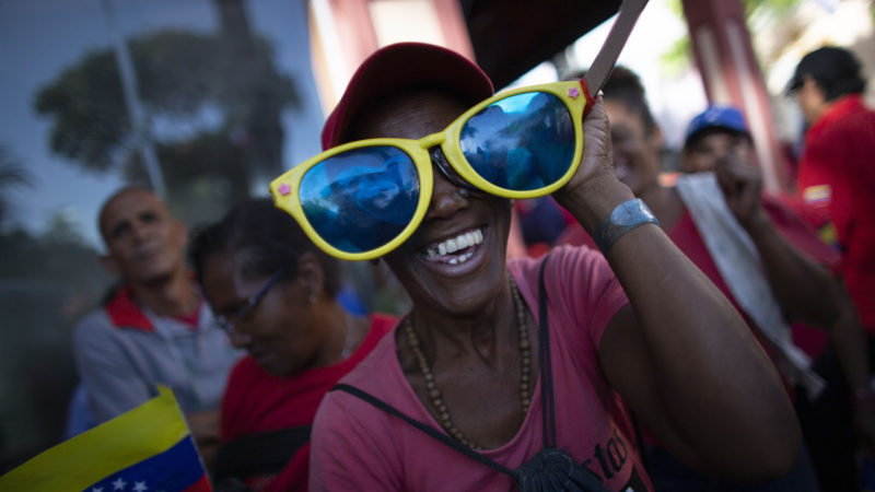 A woman dances and smiles during a protest against new sanctions by the administration of US President Donald Trump that affect CONVIASA, in Caracas, Venezuela, Monday, Feb. 10, 2020. US Treasury Secretary Steven T. Mnuchin said in a statement last Friday that Maduro's "illegitimate regime" depends on the airline "to transport corrupt regime agents worldwide to boost support for their anti-democratic efforts, "pointing out countries like North Korea and Cuba. and Iran. AP Photo/RSS