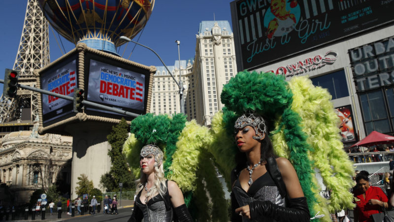 Women dressed as showgirls walk near the Paris Las Vegas hotel casino, site of a Democratic presidential debate, Wednesday, Feb. 19, 2020, in Las Vegas. Photo/RSS