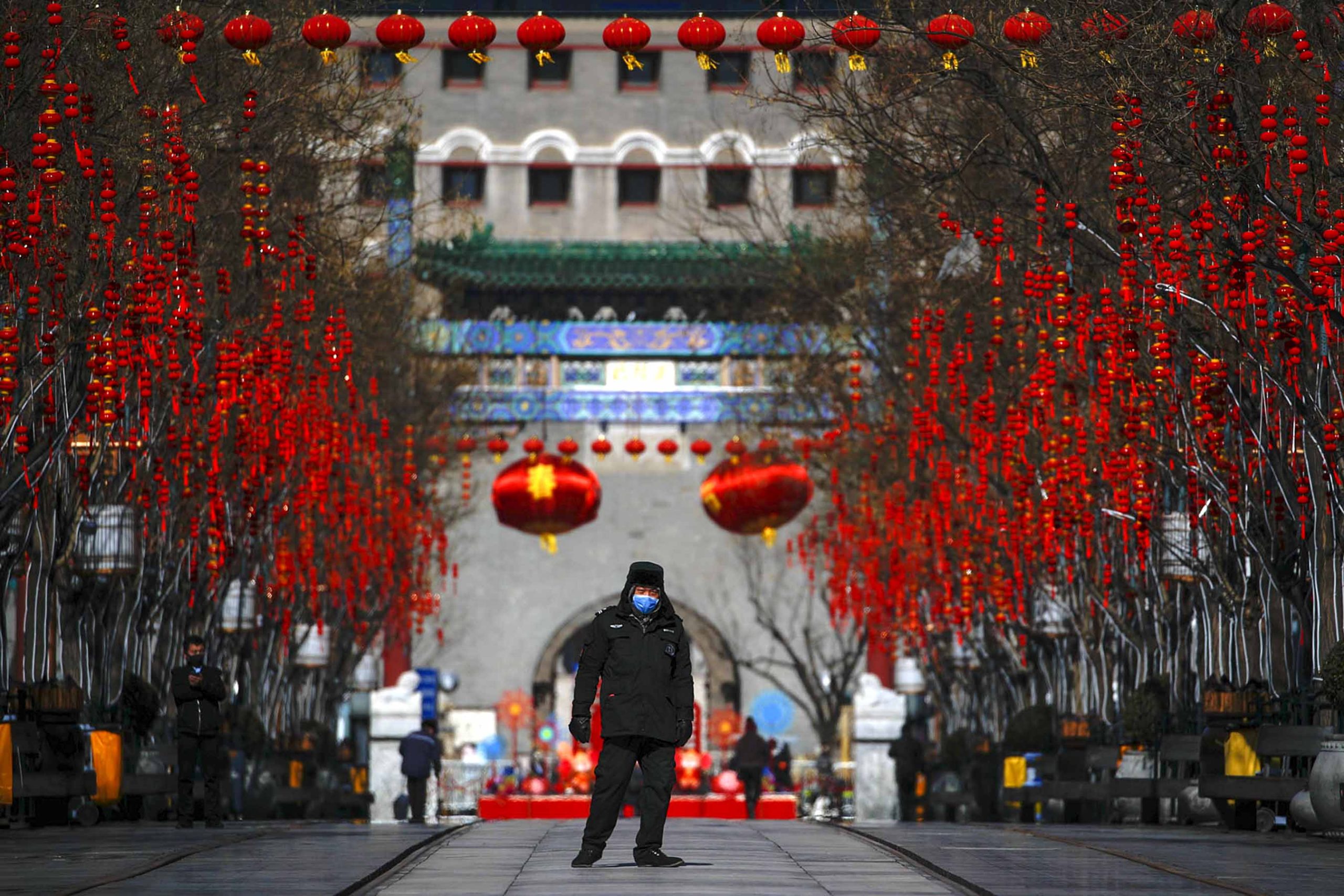 A security guard wearing a face mask walks through a quiet main Qianmen Street, a popular tourist spot, in Beijing, Sunday, Feb. 16, 2020. China reported Sunday a drop in new virus cases for the third straight day, as it became apparent that the country's leadership was aware of the potential gravity of the situation well before the alarm was sounded. (AP Photo/Andy Wong)