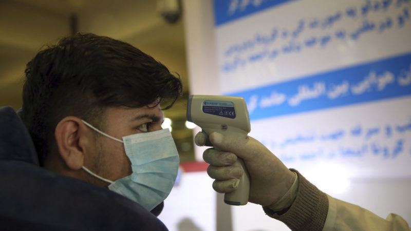 An Afghan health worker takes the temperature of a passenger as a preventive measure for Coronavirus, during screening of travelers who arrived from China, at the Hamid Karzai International Airport in Kabul, Afghanistan, Monday, Feb. 3, 2020. Screening has begun in all airports and land ports in Afghanistan, especially of those who arrive from China. (AP Photo/RSS