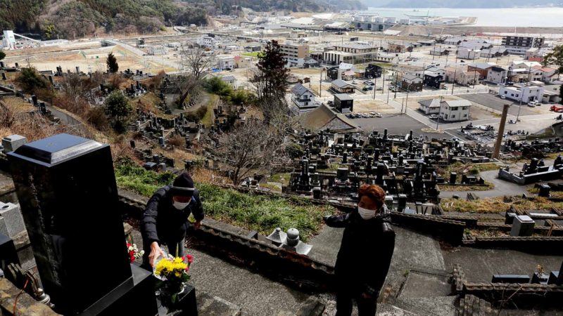 People lay flowers on their relatives' graves at a cemetery in Otsuchi, Iwate prefecture on March 11, 2020 on the ninth anniversary of the 2011 tsunami disaster. - Japan marked the ninth anniversary of the killer tsunami that triggered the Fukushima nuclear meltdown, but fears about the new coronavirus forced a scaling back of public commemorations. (Photo by STR / JIJI PRESS / AFP) / Japan OUT