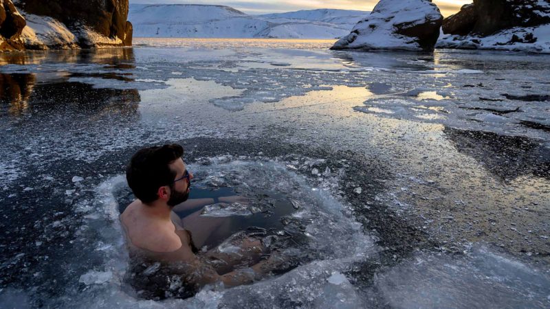 A participant baths in the waters of an ice-covered lake in southwestern Iceland during a seminar on February 1, 2020 in Kleyfarvatn, near Reykjavik. - Using slow, deliberate movements and deep breathing, bathers immerse themselves in the waters of an ice-covered lake in southwestern Iceland. The temperature above the frozen lake of Kleifarvatn, one of country's deepest, is minus six degrees Celsius (21.2 degrees Fahrenheit). (Photo by Halldor KOLBEINS / AFP)