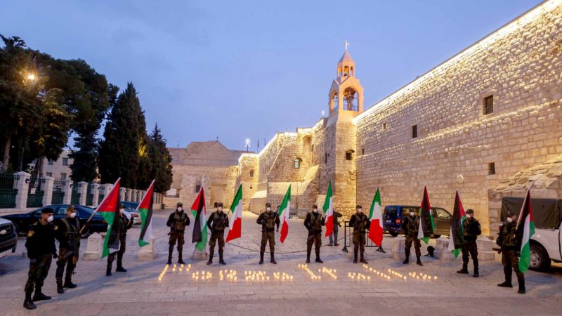 (200316) -- BETHLEHEM, March 16, 2020 (Xinhua) -- A member of Palestinian security forces lights a candle as others carry Palestinian and Italian flags showing signs of solidarity with Italy, which has been under lockdown due to the outbreak of COVID-19, in front of the closed Church of Nativity in the West Bank city of Bethlehem on March 15, 2020. (Photo by Luay Sababa/Xinhua)