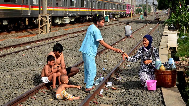 A family, who lives next to railway tracks, purchases traditional medicine in Bekasi, West Java on April 3, 2020, as a preventive measure against the COVID-19 coronavirus. (Photo by REZAS / AFP)