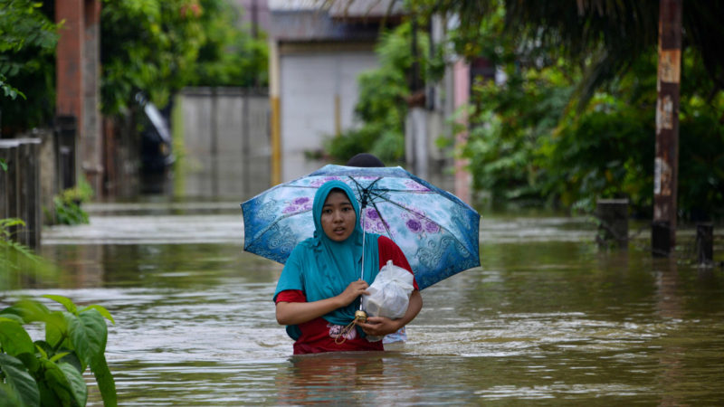 A woman wades through a flooded neighbourhood following three days of heavy rain in Banda Aceh on May 9, 2020. (Photo by CHAIDEER MAHYUDDIN / AFP)