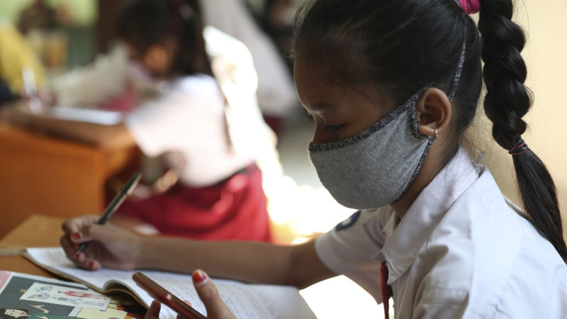 An Indonesian student wears a face mask to help curb the spread of the new coronavirus as she accesses free wifi on her mobile phone at Jatirahayu village office in Bekasi on the outskirts of Jakarta, Indonesia, Wednesday, July 29, 2020. (AP Photo/RSS