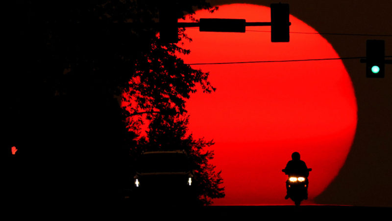 A motorcyclist is silhouetted against the setting sun, Sunday, Sept. 20, 2020, in Shawnee, Kan. Sunsets have been more vibrant than normal recently as smoke form western wildfires drifts across the United States. (AP Photo/Charlie Riedel)