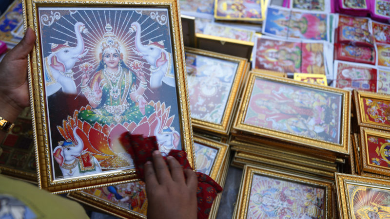 A Nepalese vendor cleans a photograph of goddess Laxmi as she waits for customers at the Ason market during the first day of Tihar festival in Kathmandu, Nepal, Friday, Nov. 13, 2020. Tihar festival which is also known as Yama Panchak is celebrated for five days. Hindus decorate their houses, worship Lakshmi, the goddess of wealth, and various animals like crow, dog, cow and ox during this festival of lights. (AP Photo/RSS)